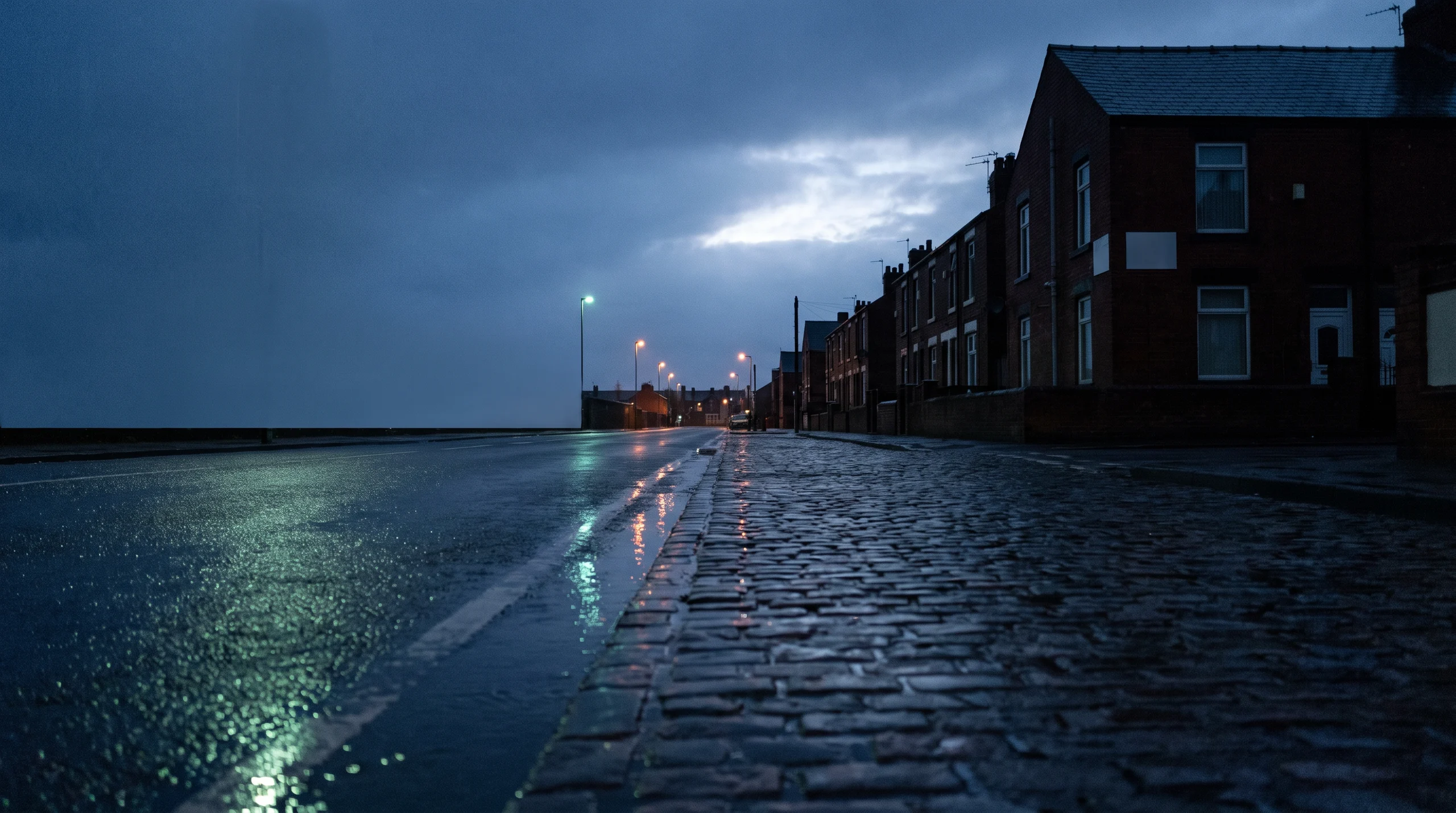 Wet cobbles and terraced houses at dusk, lights on the water
